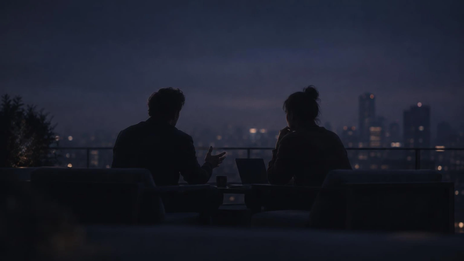 Two co-founders talking through a plan on a rooftop at dusk