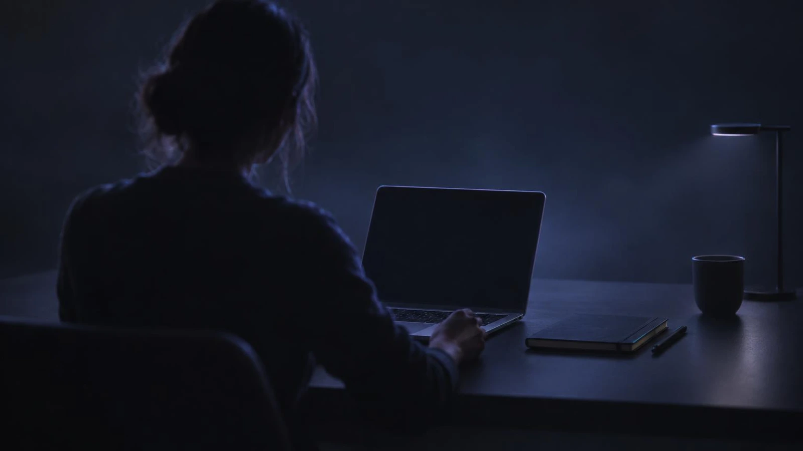 A person setting up a first desk with a laptop and a notebook