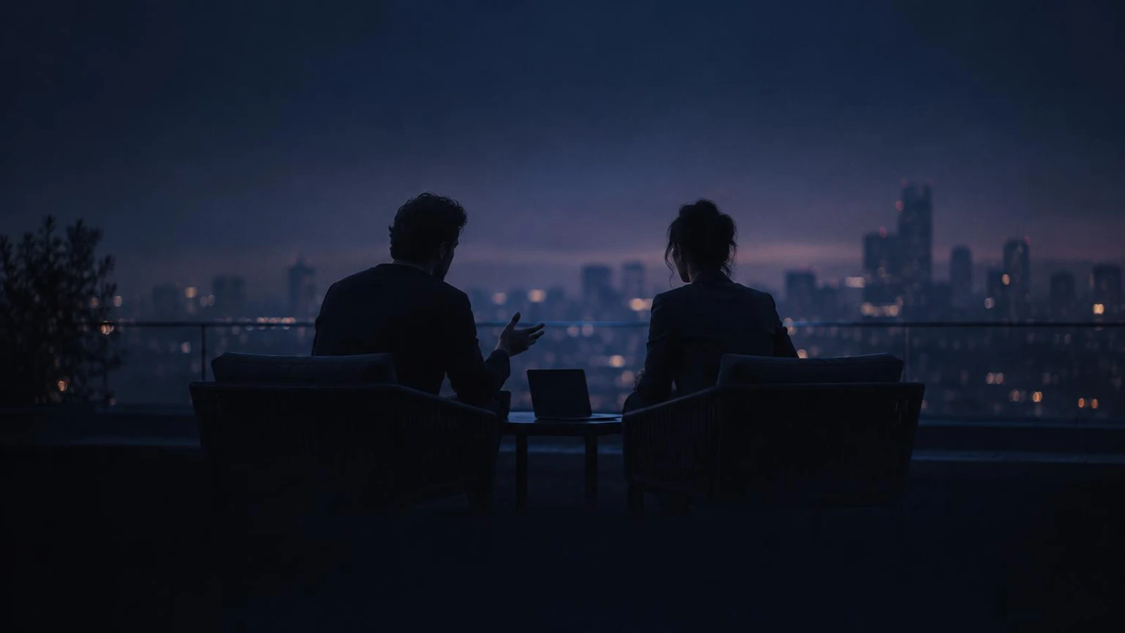 Two co-founders talking through a plan on a rooftop at dusk